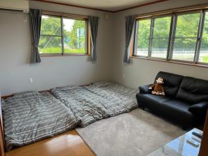 a bedroom with a bed and a teddy bear sitting on a couch at 暖炉の家 田舎自然有り大家族グループ利用BBQ日本の真ん中Mie Suzuka Ise in Tsu