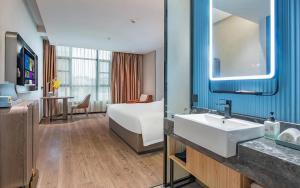une chambre d'hôtel avec un lit et un lavabo dans l'établissement Echarm Hotel Guangzhou Jiahe Helong Branch, à Canton