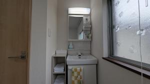 Un baño pequeño con lavabo y espejo. en Ippaku 一泊, en Izumisano