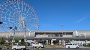 ein großes Riesenrad auf einem Parkplatz mit Autos in der Unterkunft Ippaku 一泊 in Izumi-Sano
