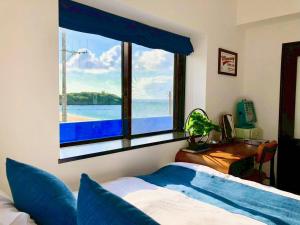a bedroom with a window with a view of the water at SEA BASE Onna in Onna