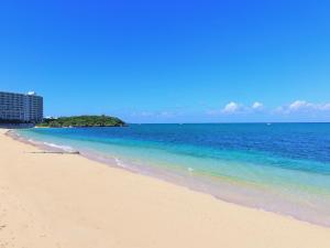 a beach with blue water and a building in the background at SEA BASE Onna in Onna