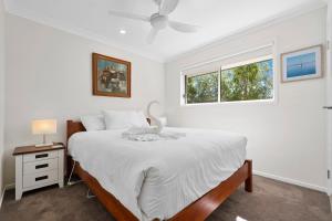 ein weißes Schlafzimmer mit einem Bett und einem Fenster in der Unterkunft The Wren's Nest in Sandstone Point