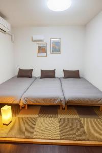two beds sitting in a room with ainylinylinylinylinylinylinylinyl at 通天閣徒歩1分3ベッド in Osaka