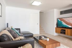 a living room with a leather couch and a flat screen tv at Beachfront Manly Apartment With Balcony & Parking in Sydney