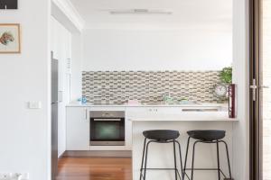 a kitchen with two stools and a counter with a tv at Beachfront Manly Apartment With Balcony & Parking in Sydney