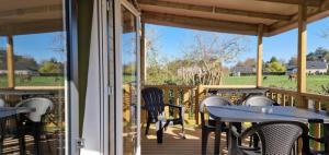 a patio with tables and chairs on a deck at ZEcamping 3 étoiles animaux acceptés à proximité des plus beaux sites in Pordic
