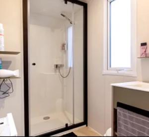 une douche avec une porte vitrée dans une salle de bain dans l'établissement Camping 3 étoiles - ccbc0hb, à Pordic 34 autres photos
