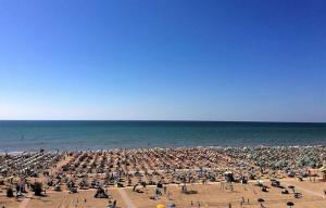 a large crowd of people on a beach with the ocean at Apartments in Bibione 54671 in Lo Stallone +2 photos