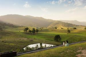 Ein Brautpaar steht auf einer Mauer mit Blick auf ein Feld in der Unterkunft Rileysview in Kilcoy