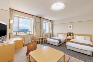 a hotel room with two beds and a table at KAMENOI HOTEL Ichinoseki in Ichinoseki