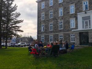 un groupe de personnes assises à une table devant un bâtiment dans l'établissement Aubergeducouvent, à Saint-Casimir