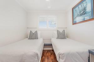 Absolute Beachfront Apartments 3T في لينوكس هيد: سريرين في غرفة بها نافذة +14 صورة