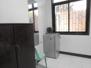 a room with a refrigerator and a chair and a window at Pacifico Seaside Lodge in Moalboal