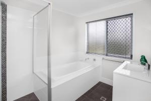 une salle de bain blanche avec une baignoire et un lavabo dans l'établissement Comfortable 3-Bed Retreat Close Parks, à Brisbane