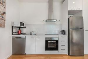 Una cocina con gabinetes blancos y electrodomésticos de acero inoxidable. en Comfy Studio with Shared Backyard near Racecourse, en Carnegie 3 fotos más