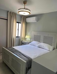 a bedroom with a large white bed with a light at BOvibe Condo - 2 Suites avec Piscine - Pueblo Bávaro in Punta Cana