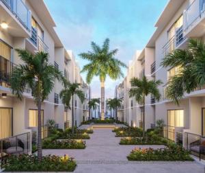 une cour intérieure d'un immeuble avec des palmiers dans l'établissement BOvibe Condo - 2 Suites avec Piscine - Pueblo Bávaro, à Punta Cana