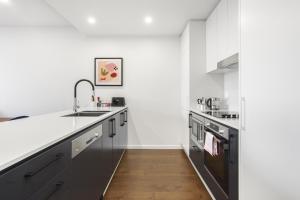 une cuisine avec des murs blancs et des appareils en acier inoxydable dans l'établissement Boutique Unit with Huge Terrace near Cafes & Shops, à Kingston 