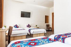 Cette chambre comprend 4 lits et une télévision murale. dans l'établissement Solief Hotel, à Tachkent