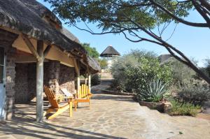 a patio with chairs and a thatch roof at Outeniqua Guest Farm in Okahandja