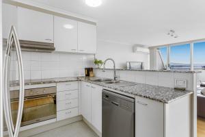 eine weiße Küche mit Spüle und Geschirrspüler in der Unterkunft 2-Bed Unit with Balcony BBQ & Stunning Lake Views in Belconnen