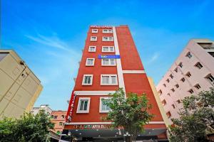 a tall red building with a blue sign on it at Hotel Abhimanyu Villa in Hyderabad