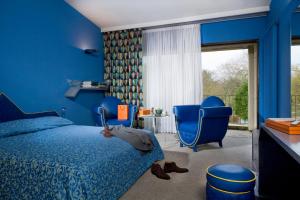 a blue bedroom with a bed and a blue chair at Relais du Bois Saint Georges - Hôtel de Charme in Saintes