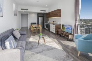 a living room with a couch and a tv and a table at River-View Unit with Rooftop Pool near Museums in Brisbane +6 photos