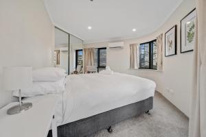 - une chambre blanche avec 2 lits et un miroir dans l'établissement Central 2-bed Apartment with Pool, Gym and Spa, à Canberra