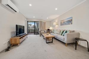 un salon avec un canapé et une télévision dans l'établissement Central 2-bed Apartment with Pool, Gym and Spa, à Canberra