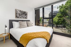 a bedroom with a white bed and a large window at Chic 3-Bed in Central with Pool, Sauna and Gym in Canberra