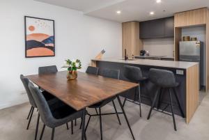 a kitchen with a wooden table and chairs at Chic 3-Bed in Central with Pool, Sauna and Gym in Canberra +9 photos