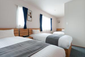 a hotel room with three beds with blue curtains at Villas Fuji Terrace ヴィラス富士テラス in Fujikawaguchiko