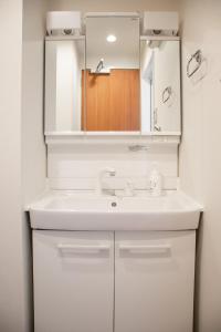 ein weißes Badezimmer mit Waschbecken und Spiegel in der Unterkunft Hotel S-Presso West - Vacation STAY 9086 in Osaka + 13 Fotos