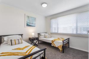 Un dormitorio con dos camas y una ventana en Cosy 2-Bedroom Seaside Unit Steps from Beach, en Maroochydore