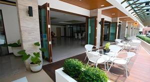 eine Terrasse mit weißen Stühlen und Tischen auf einem Gebäude in der Unterkunft The Capital Hotel in Roi Et