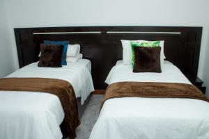 two beds in a room with white and brown pillows at New Dawn Lodge in Lilongwe