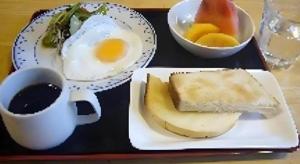 a tray with a plate of eggs and bread and a cup of coffee at Business Hotel Tsuwano in Tsuwano