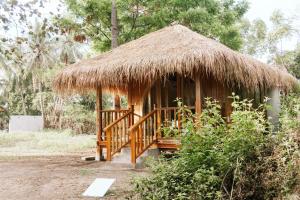 a hut with a grass roof and a wooden porch at The Good House in Gili Air