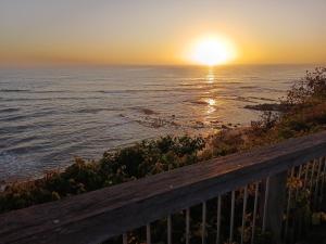 een zonsondergang boven de oceaan met een houten reling bij Bonnys Bliss in Bonny Hills