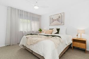 ein weißes Schlafzimmer mit einem Bett und einem Fenster in der Unterkunft The Tides - Luxe Beach House Mornington in Mornington