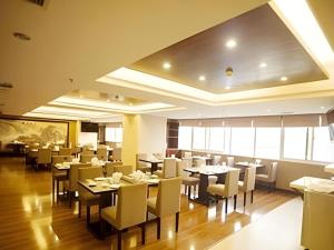 a restaurant with tables and chairs in a room at Wuhan Yamao Hengsheng Hotel in Wuhan