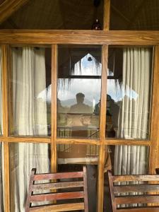 a man sitting at a table looking out of a window at Elim Retreat kanthalloor in Kanthalloor