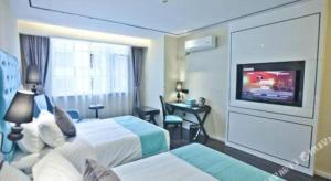a hotel room with two beds and a flat screen tv at Xana Lite Leshan Haochi Street Branch in Leshan
