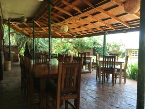 uma sala de jantar com mesas e cadeiras sob um telhado em Surjios Guest House em Jinja