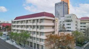 ein Gebäude mit rotem Dach in einer Stadt in der Unterkunft Jinjiang Inn Select Tianjin Xiaobailou Metro Station in Tianjin