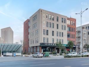 un bâtiment avec des voitures garées devant une rue dans l'établissement Xana Hotelle·Ji'nan Hi-tech Zone Century Avenue Tangye, à Jinan