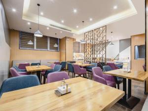 a restaurant with wooden tables and purple chairs at Borrman Hotel Fangchenggang High-speed Railway North Station Crystal International in Fangcheng