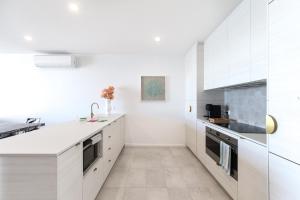 une cuisine blanche avec des armoires blanches et un évier dans l'établissement Bayfront Holiday Retreat with Parking, à Batemans Bay
